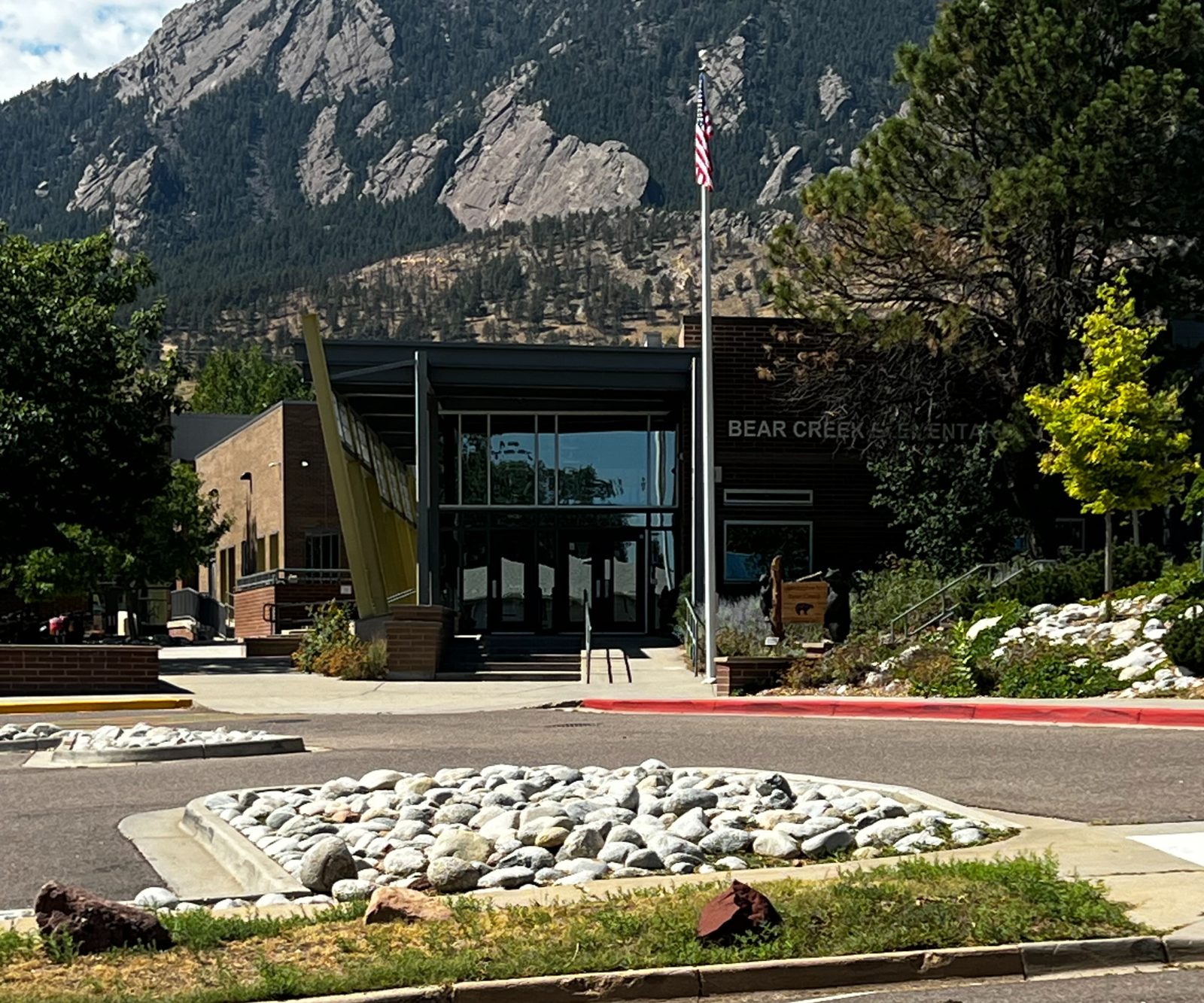 Bear Creek Elementary’s entrance and flagpole, with the Flatirons behind it